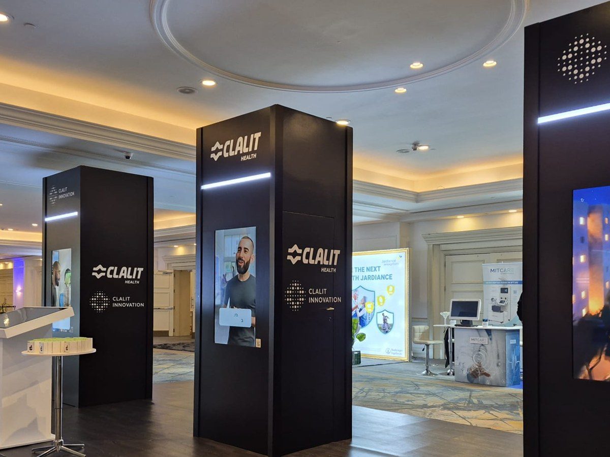 Three dark freestanding totems with lit strips and vertical screens, standing on a dark timber deck.