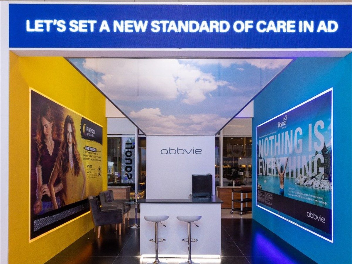 Symmetrical stand with a printed sky ceiling, colour-blocked yellow and blue walls either side.