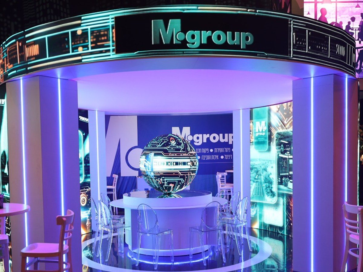 A circular pavilion under a curved LED fascia, columns of vertical light around a lit counter on a mirror floor.
