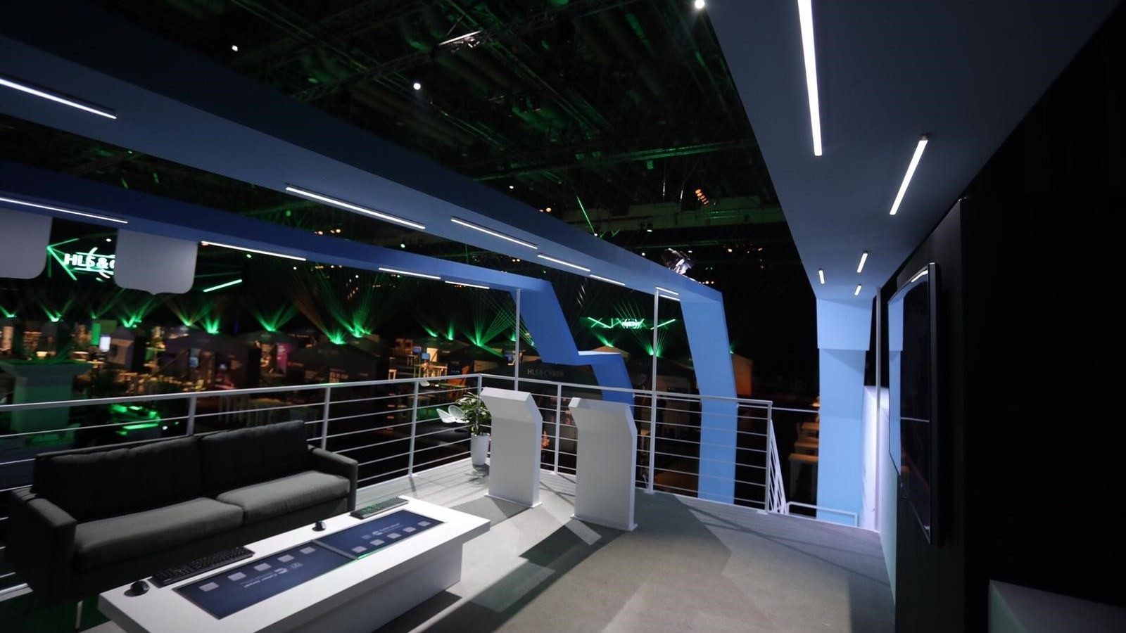 The view from the upper deck of the two-storey build, out over the exhibition floor with green laser fans across the hall.