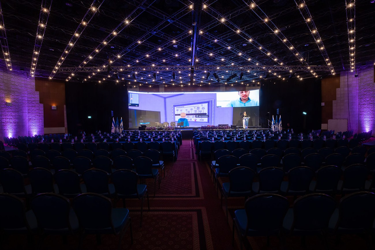 The same hall built and empty before the doors open, rows of chairs under lines of warm ceiling lights.