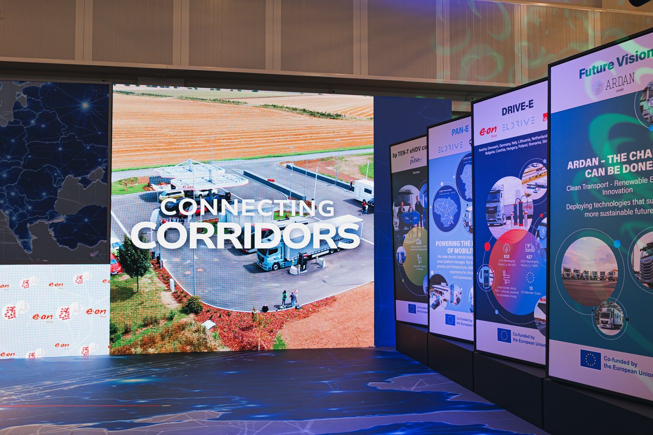 קיר LED שעליו הכיתוב Connecting Corridors, ולצדו שורת טוטמים של השותפים.